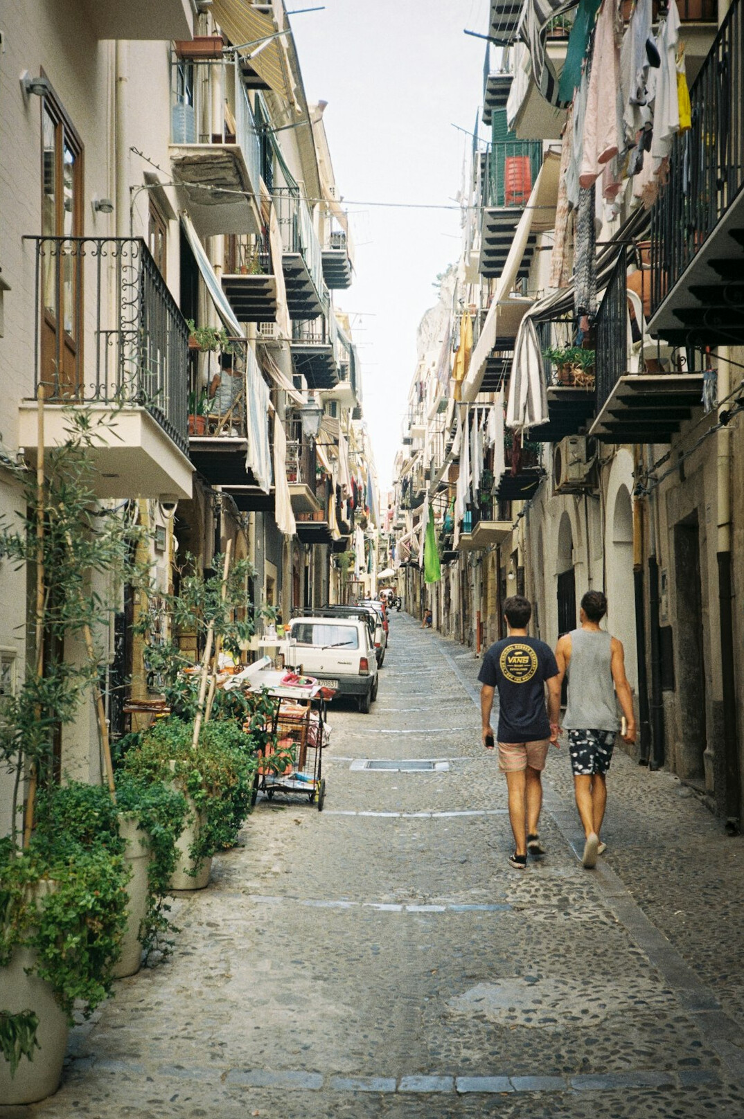 Narrow city street with pedestrians walking past shops